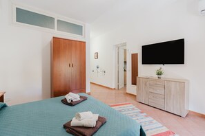 Una camera da letto con un letto, un armadio, una televisione e un bagno visibile attraverso una porta aperta.