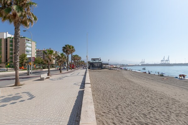 A beachside promenade with palm trees, a clear sky, and a view of the sea.