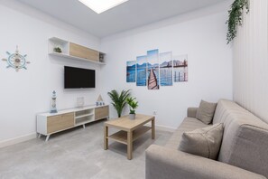 A modern living room with a sofa, a coffee table, a TV, and artwork on the wall.