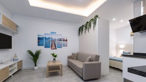 Un salon moderne avec un canapé, une table basse, un téléviseur à écran plat et des œuvres d’art accrochées au mur.