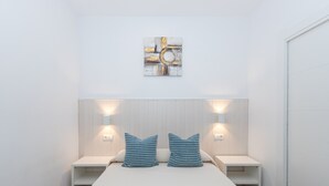 Une chambre à coucher avec un lit, deux tables de chevet et des lampes fixées au mur.