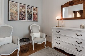 Una habitación con un aparador blanco, una silla, una mesita redonda y un espejo fijado a la pared.
