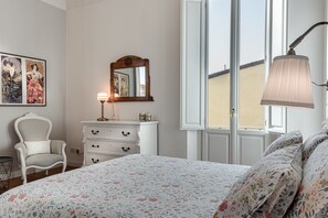 Un dormitorio con cama, cómoda, silla y un ventanal grande.