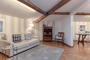 A living room with a sofa, a glass coffee table, a wooden cabinet, and a dining table with chairs.