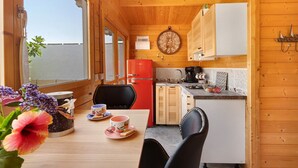 Puuinen mökki, jossa on ruokailutila, keittiö ja seinällä oleva kello.