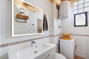 Une salle de bain avec un lavabo blanc, un miroir, un porte-serviettes et un radiateur.