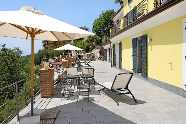 An outdoor patio with tables and chairs, umbrellas, and a brick fireplace.