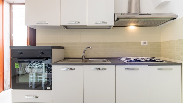 A compact kitchen with white cabinets, a stainless steel sink, and a built-in oven. - Studio Apartment 'Casa Roby' with Wi-Fi and Air Conditioning (Ceglie Messapica)