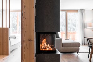 A modern living room with a fireplace, a sofa, and a view of a snowy landscape through large windows.
