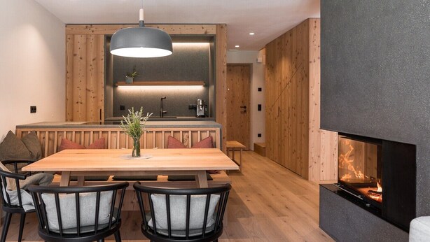 Une cuisine moderne agrémentée d’éléments en bois, un coin repas avec une table et des chaises en bois, et une cheminée.