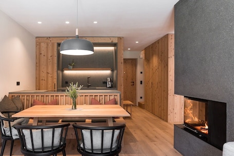 A modern kitchen with wooden accents, a dining area with a wooden table and chairs, and a fireplace.