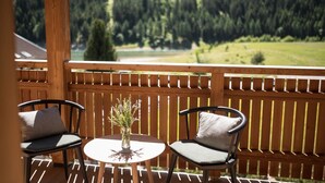Une terrasse en bois avec deux chaises et une table, offrant une vue sur un paysage boisé.