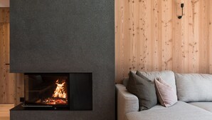 Un salon moderne avec une cheminée intégrée, un canapé gris et un lambris en bois sur le mur.