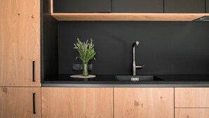 A kitchen with a black countertop, a stainless steel faucet, and a small vase with green plants. - Sunnseit Luxury Apartment 3 – Private Garden & Sauna, Lake View (Ultimo)
