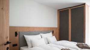 A modern hotel room with a wooden headboard, a grey accent wall, and a large wardrobe. - Sunnseit Luxury Apartment 3 – Private Garden & Sauna, Lake View (Ultimo)