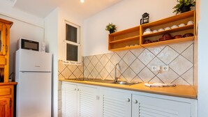 A kitchen with a refrigerator, a sink, wooden cabinets, and a tiled backsplash. - "Pujols 16" Apartment with a Balcony and Air Conditioning (Es Pujols)