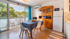 A compact kitchen with a dining area, a wooden cabinet, and a built-in microwave. - "Pujols 16" Apartment with a Balcony and Air Conditioning (Es Pujols)
