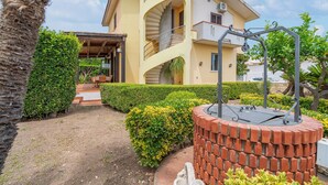 A multi-story building with a spiral staircase, a brick outdoor fireplace, and well-maintained hedges.