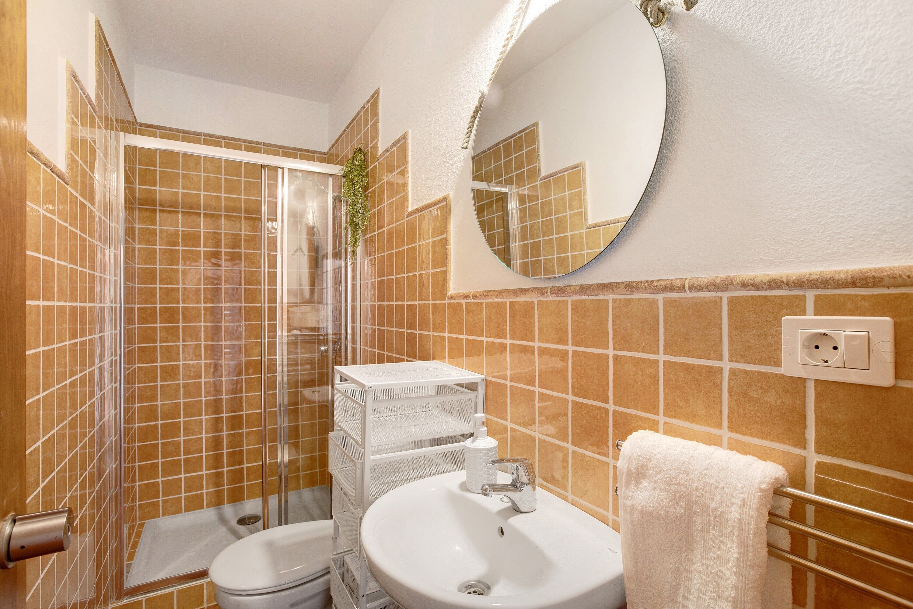 Een badkamer met douche, toilet, wastafel en spiegel.