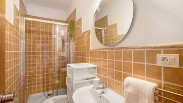 Een badkamer met douche, toilet, wastafel en spiegel.