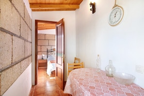 Une pièce avec un lit, une porte en bois, une horloge murale et une petite table sur laquelle se trouvent un bol et des bouteilles.