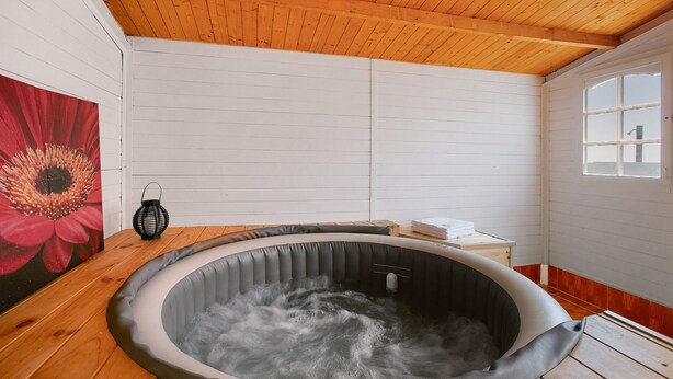 A hot tub in a room with wooden ceiling and white walls, a window, and a red flower painting. - Holiday Apartment "Verode" with Sea View, Shared Terrace & Wi-Fi (Arico)