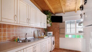 A kitchen with a sink, microwave, and washing machine, wooden ceiling, and a window with a view. - Holiday Apartment "Verode" with Sea View, Shared Terrace & Wi-Fi (Arico)