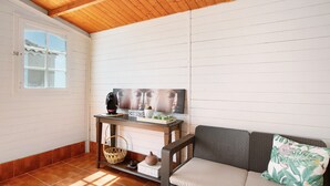 A room with a wooden ceiling, a white wall with horizontal lines, a window, a sofa with a cushion, a table with a vase, and a framed picture. - Holiday Apartment "Verode" with Sea View, Shared Terrace & Wi-Fi (Arico)