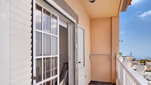 A balcony with a white railing, a sliding glass door, and a view of the street. - Holiday Apartment "Los Morales" with Sea View, Shared Terrace & Wi-Fi (Arico)