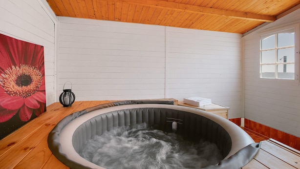 A hot tub in a room with wooden ceiling and white walls, a window, and a red flower painting. - Holiday Apartment "Los Morales" with Sea View, Shared Terrace & Wi-Fi (Arico)