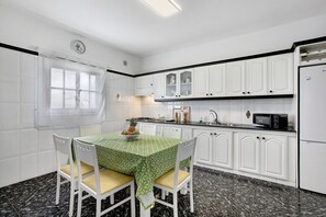 Une cuisine avec des meubles blancs, un four à micro-ondes et une table à manger avec des chaises.