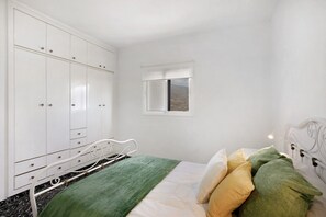 Une chambre à coucher avec un lit, une armoire, une fenêtre et une vue sur l’extérieur.