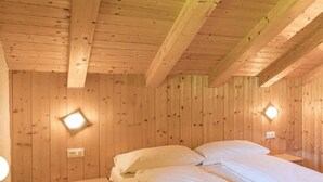 A wooden room with a bed, bedside table, and wall-mounted light. - Apartment 'Brugghof Brugg' with Mountain View, Balcony and Wi-Fi (Schnals)