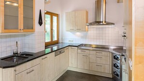 A kitchen with wooden cabinets, a stainless steel range hood, a double sink, and a window with a view of greenery. - Apartment 'Brugghof Brugg' with Mountain View, Balcony and Wi-Fi (Schnals)