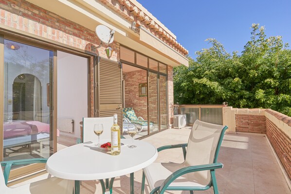 A patio with a table and chairs, a bottle of wine, and a glass. - Holiday Apartment "Ombú" with Sea View, Private Terrace & Wi-Fi (La Herradura)