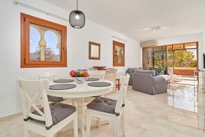 A dining area with a white table and chairs, a bowl of fruit, and a sofa in the background. - Holiday Apartment "Ombú" with Sea View, Private Terrace & Wi-Fi (La Herradura)
