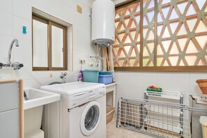 A laundry area with a washing machine, a sink, and a window with a lattice design. - Holiday Apartment "Ombú" with Sea View, Private Terrace & Wi-Fi (La Herradura)
