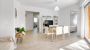 A modern living room with a dining area, a TV, and a staircase leading to another level. - Apartment 'Roma' with Shared Pool, Wi-Fi and Air Conditioning (Platja de Gandia)