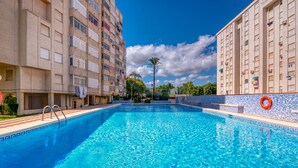 A swimming pool with a tiled edge, surrounded by buildings. - Apartment 'Roma' with Shared Pool, Wi-Fi and Air Conditioning (Platja de Gandia)