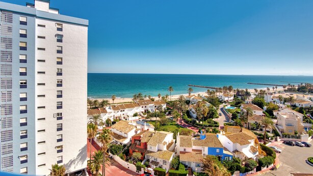 A coastal town with a mix of residential buildings, a prominent white high-rise, and a beach in the background. - Apartment 'Playa Puig' with Shared Pool, Wi-Fi and Air Conditioning (El Puig de Santa Maria)