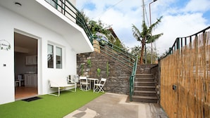 A modern house with a stone wall, a wooden fence, and a staircase leading to a balcony. - Studio Apartment 'Babosas Charm' with Mountain View, Wi-Fi and Air Conditioning (Funchal)