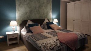 Une chambre à coucher comprenant un lit, des tables de chevet, une armoire et une tête de lit à motifs.