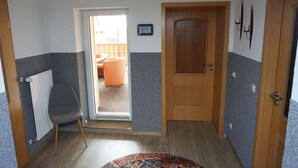 Un couloir avec une porte en bois, un radiateur et une chaise.