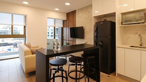 A modern kitchen with a black refrigerator, white cabinets, and a bar area with stools.