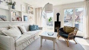 Un salon moderne avec un canapé, une table basse, un fauteuil en osier et une cheminée.
