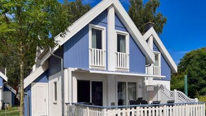Une maison à deux étages avec un porche blanc et une clôture blanche.