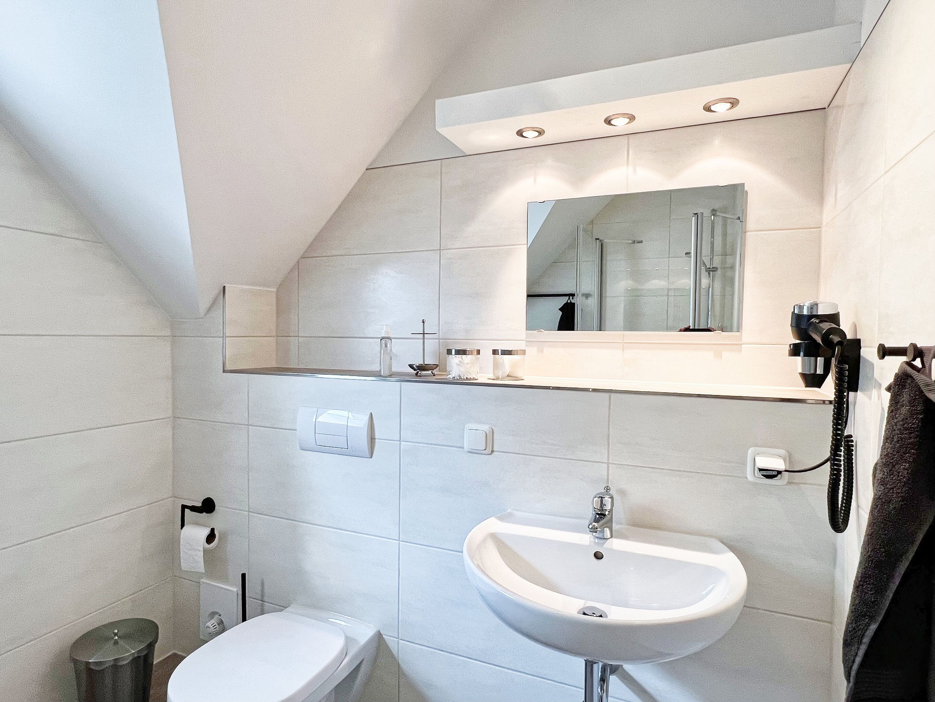 Une salle de bain moderne équipée de toilettes, d’un lavabo et d’un miroir.
