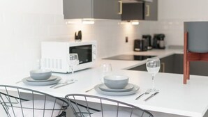 Una cucina moderna con ripiani bianchi, un forno a microonde bianco e piatti e ciotole grigie pronte per la tavola.