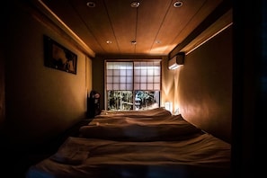 A narrow room with two beds aligned against the wall, a large window with a view of bamboo outside, and a ceiling with recessed lighting. - Kyomachiya Mitsushi / Kyoto Kyōto (Kyoto)