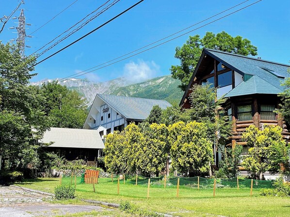 A mountain lodge with a stone pathway, wooden cabins, and lush greenery.